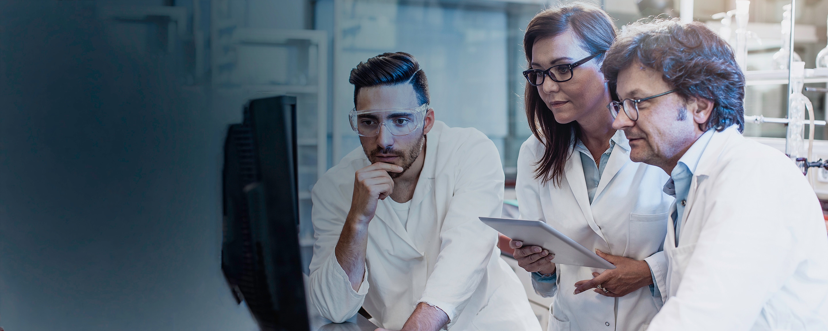 Three scientists viewing a monitor